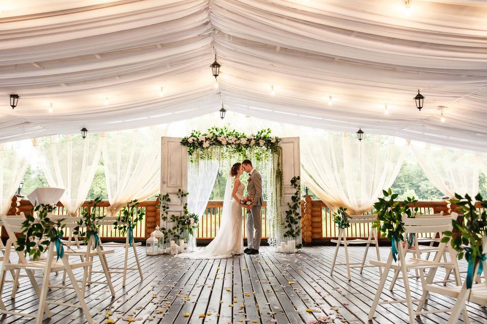 Pareja de recién casados se coge de las manos y se apoyan el uno al otro en una terraza cubierta decorada para celebrar una boda civil