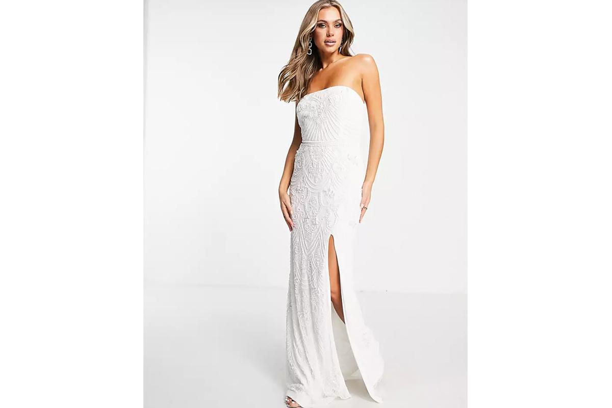 Chica rubia con el pelo suelto con un vestido de novia con escote palabra de honor y profunda abertura vertical en la falda