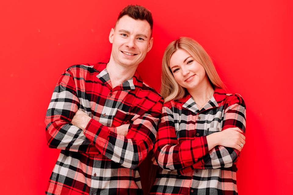 Chico y chica sobre fondo rojo con una camisa de pijama idéntica: un modelo de cuadros en blanco, gris, negro y rojo