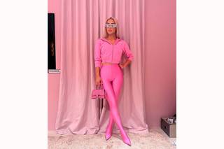 Kim Kardashian con look barbiecore a base de pant boots sudadera y minibolso en tono rosa chicle