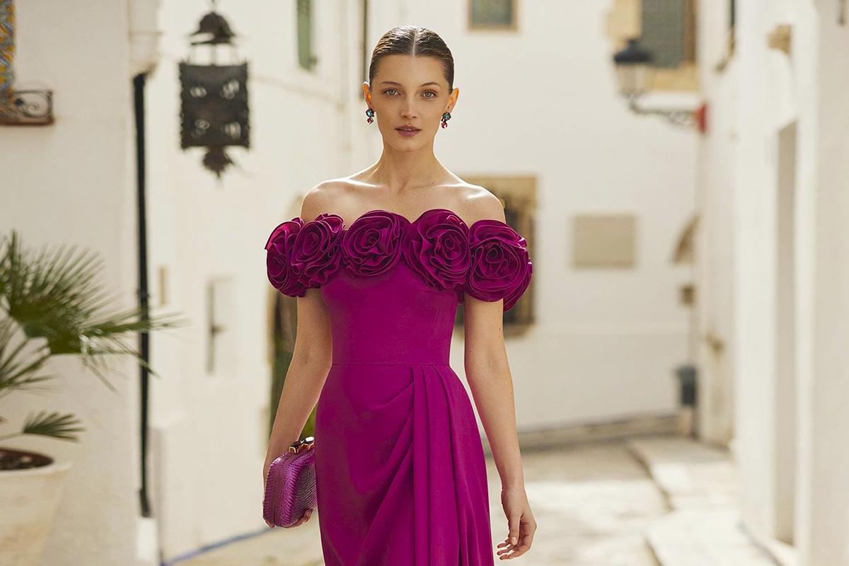 Tendencias vestidos invitada boda 2025: vestido morado con escote de hombros caídos y flores en 3D