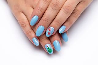 Manicura en azul clarito con dos uñas con motivos navideños