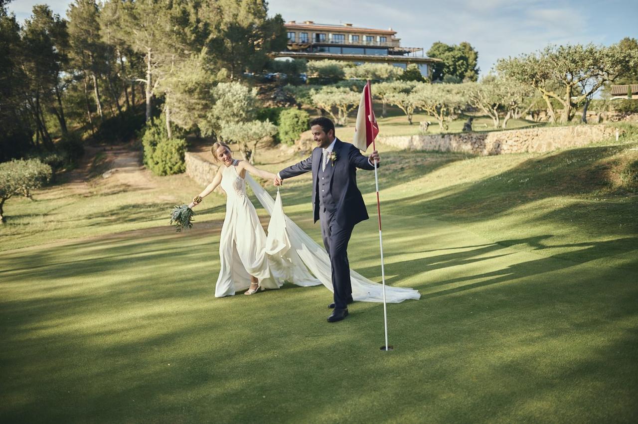 Cómo decir te quiero sin decirlo: chico con traje y chica vestida de novia cogidos de la mano y muy sonrientes en un campo de golf