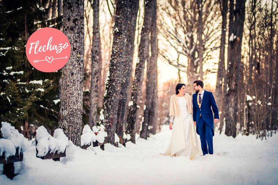 Pareja de chico y chica vestidos de boda caminan juntos de la mano por un paisaje nevado