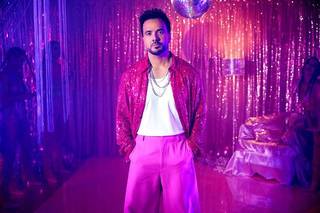 Luis Fonsi con total look barbiecore en un fondo discotequero