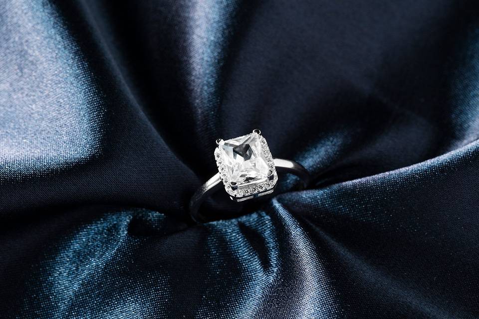 anillo de compromiso con diamante cuadrado sobre tela azul satinada