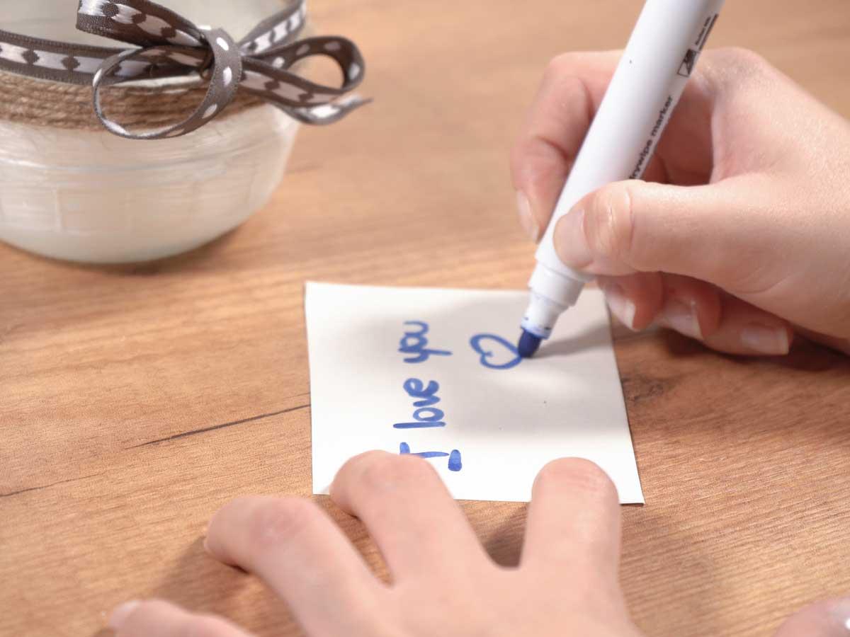 Regalo tarro con frases: manos escribiendo frases de amor para San Valentín 