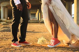 Chico con pantalón de vestir con Converse rojas y chica con un vestido blanco con Converse rosa de bota