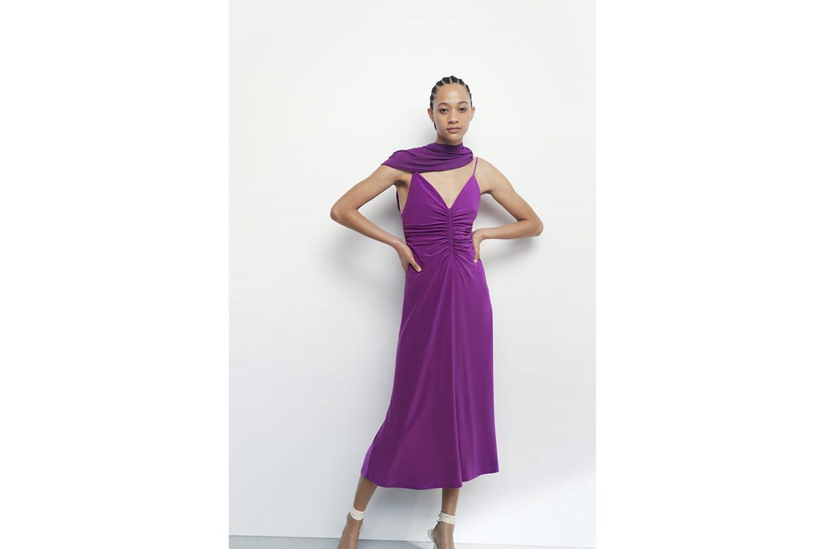 Chica mulata con el pelo peinado a la afro con vestido morado con escote en V y tirantes espagueti