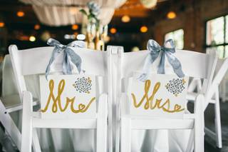 Sillas de los novios el día de la boda con carteles de Mr. y Mrs. y lazos de tela de color azul