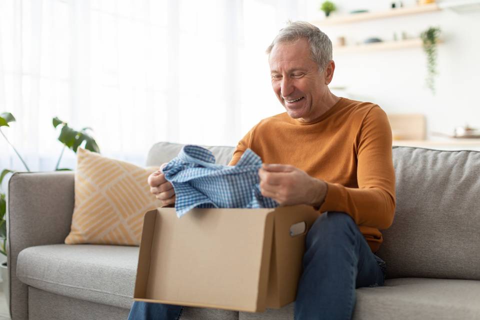 Regalos para el Día del Padre: hombre sonriente sacando una camisa de una caja de regalo