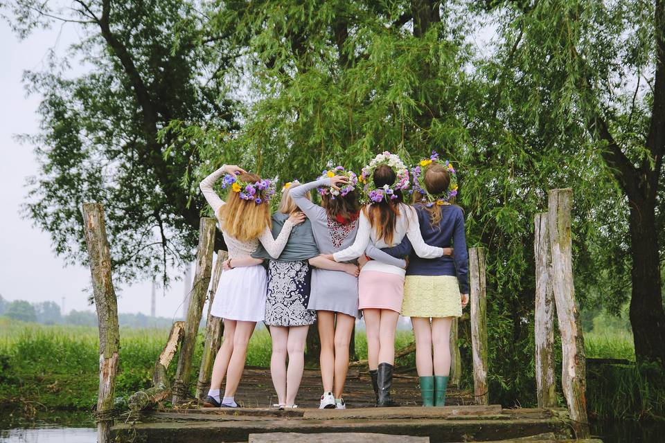Ideas despedida de soltera: grupo de amigas de espaldas y cogidas, todas con faldas cortas y coronas de flores en la cabeza