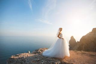 Chica con un vestido de novia de corte princesa junto a un acantilado, con el mar al fondo