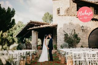 Masías para bodas con alojamiento Catalunya: pareja de chico y chica vestidos de boda se besa ante una masía en ceremonia civil al aire libre