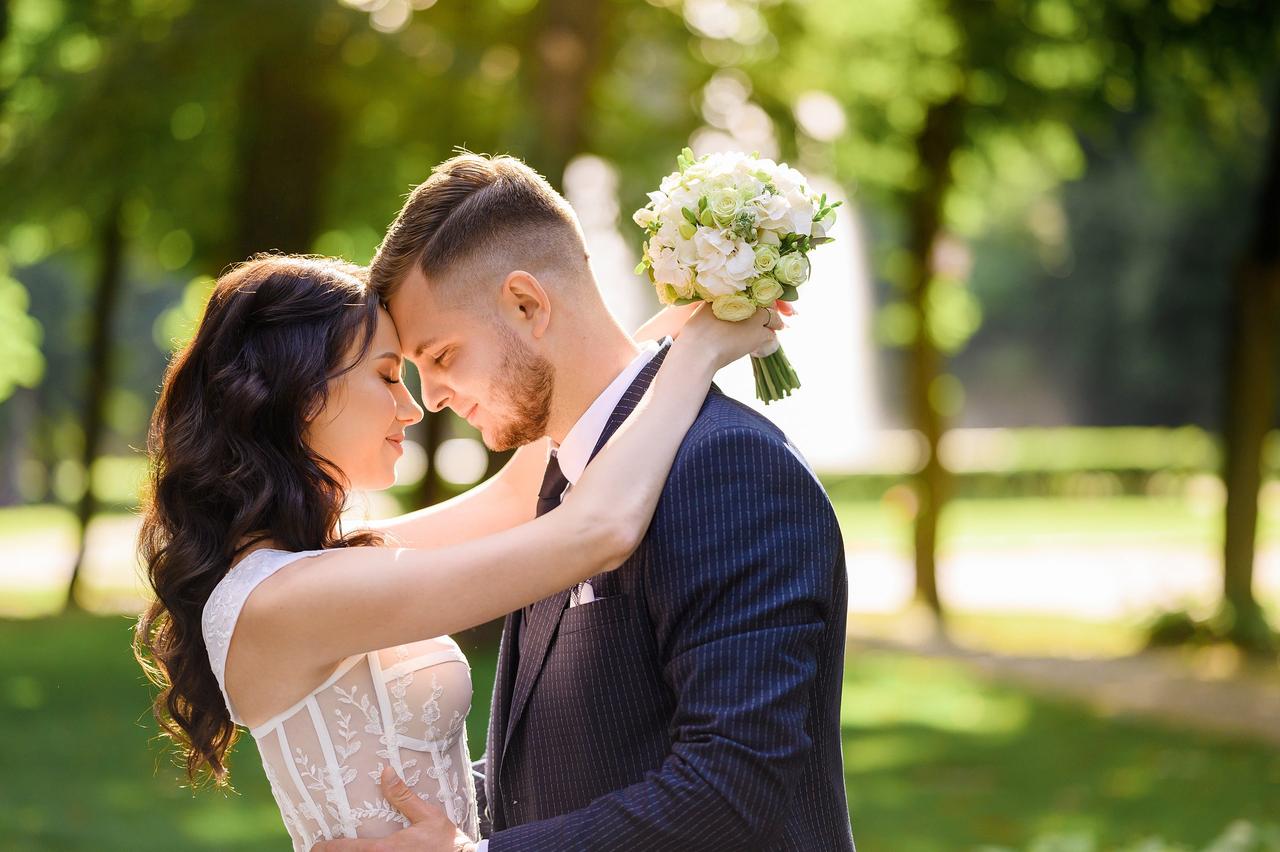 Mentiras de las mujeres: chico y chica vestidos de novios se abrazan con las frentes apoyadas