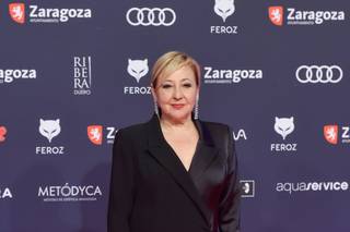 La actriz Carmen Machi posa sobre la alfombra roja de los Premios Feroz 2023 con un vestido negro de invitada largo cruzado con plumas en los puños