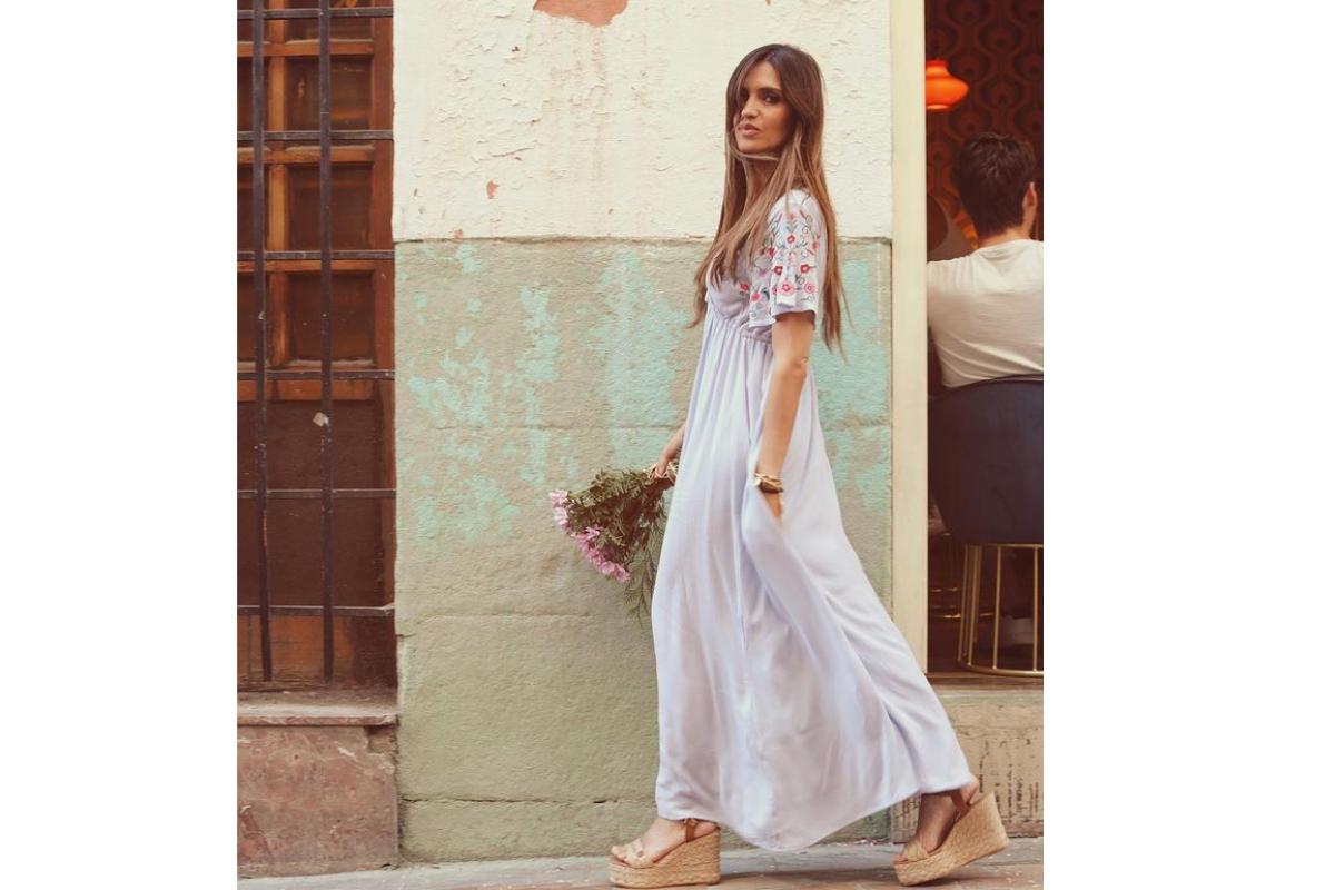 Sara Carbonero con un vestido boho y vintage con flores bordadas, manga larga y cuñas de esparto