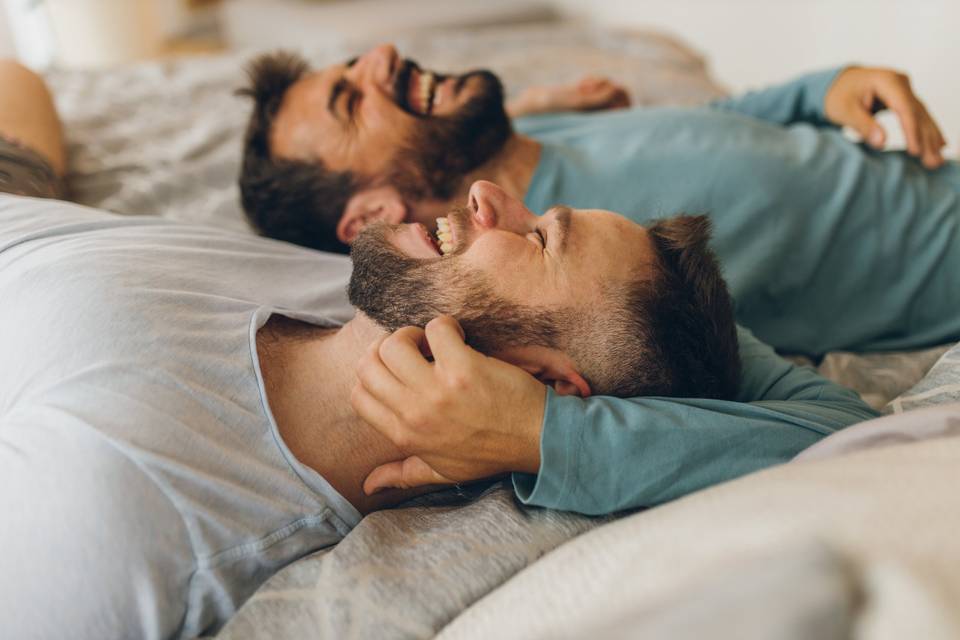 Cosas de parejas: dos chicos estirados en una cama, riéndose