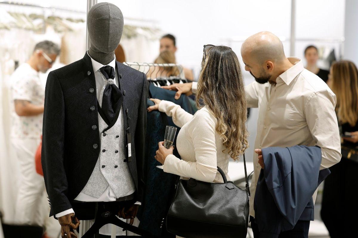 Una pareja ojeando un traje de novio en la feria Barcelona Bridal Fashion Week en el trade show