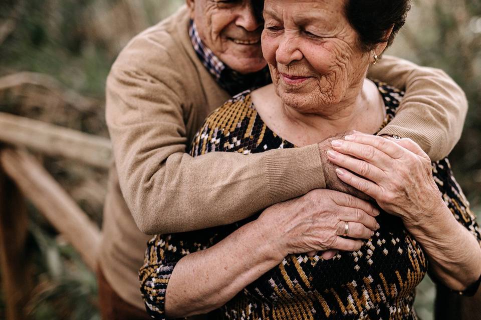 Regalo abuelos boda: un señor mayor abraza a una señora mayor mientras los dos están muy sonrientes
