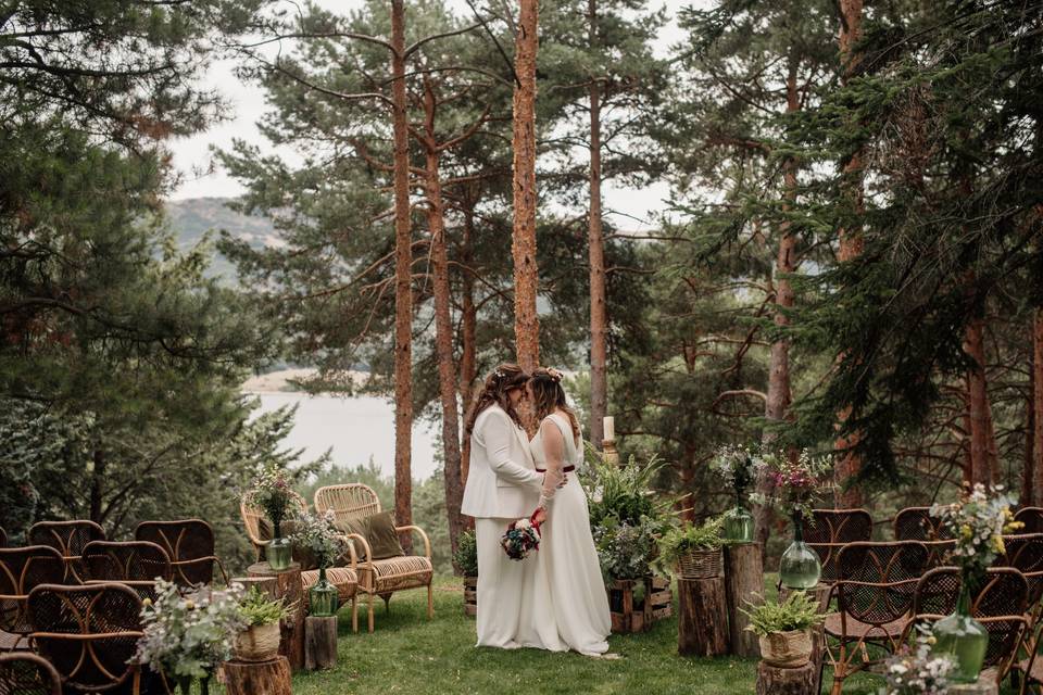Boda low cost: dos chicas vestidas de novias se abrazan en el altar de su boda civil en medio de la naturaleza
