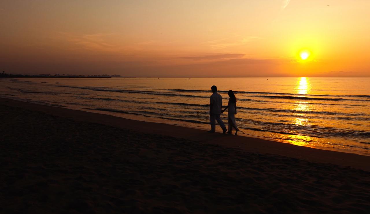 Pareja paseando al aterdecer por la playa, de ibeyonddronesvlc