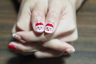 Manicura navideña 2023 con las uñas en rojo y con unos Pape Noel dibujados