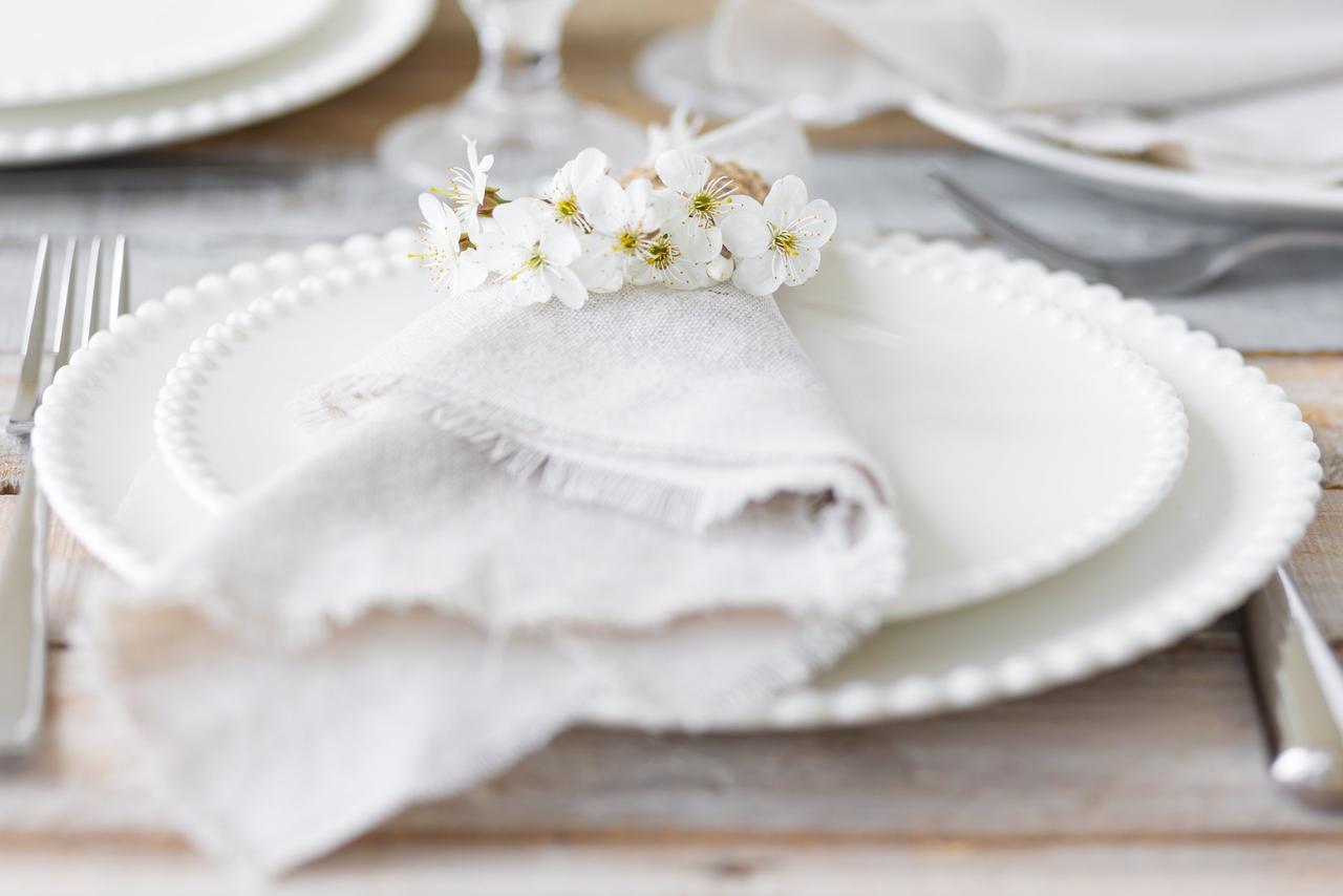 Color boda su significado: platos, servilleta y ramillete de flores en blanco
