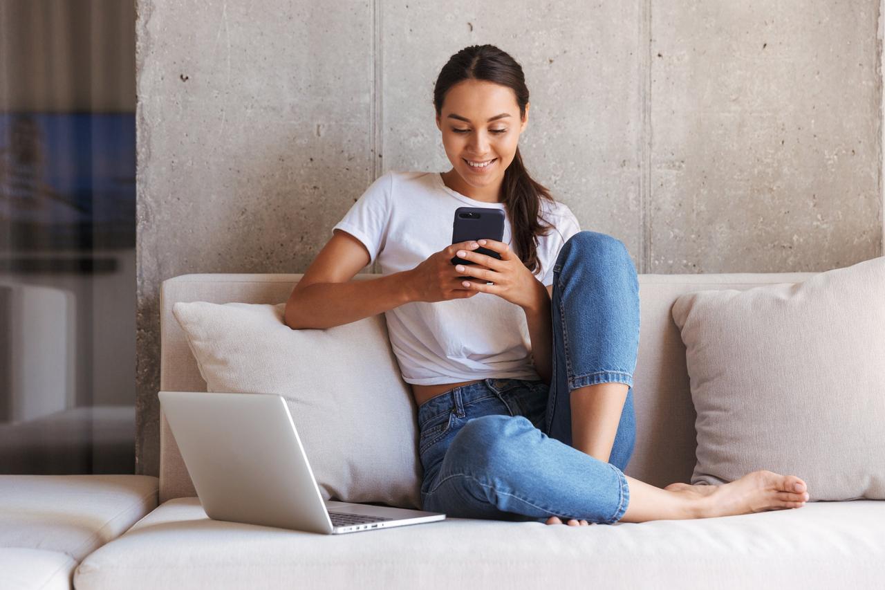 Chica joven sentada en un sofá chatea con sus amigos