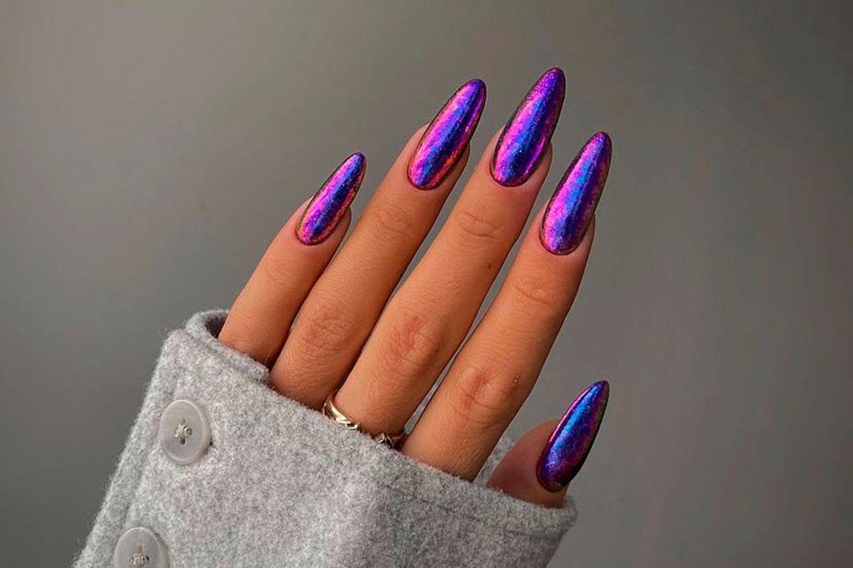 mano con uñas cromadas largas stiletto en tonos morado, azul y rosa holográfico