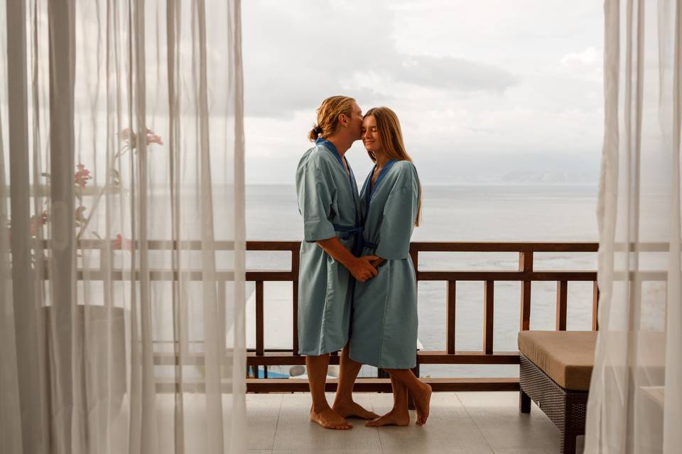 Pareja joven en albornoz en la terraza de un hotel