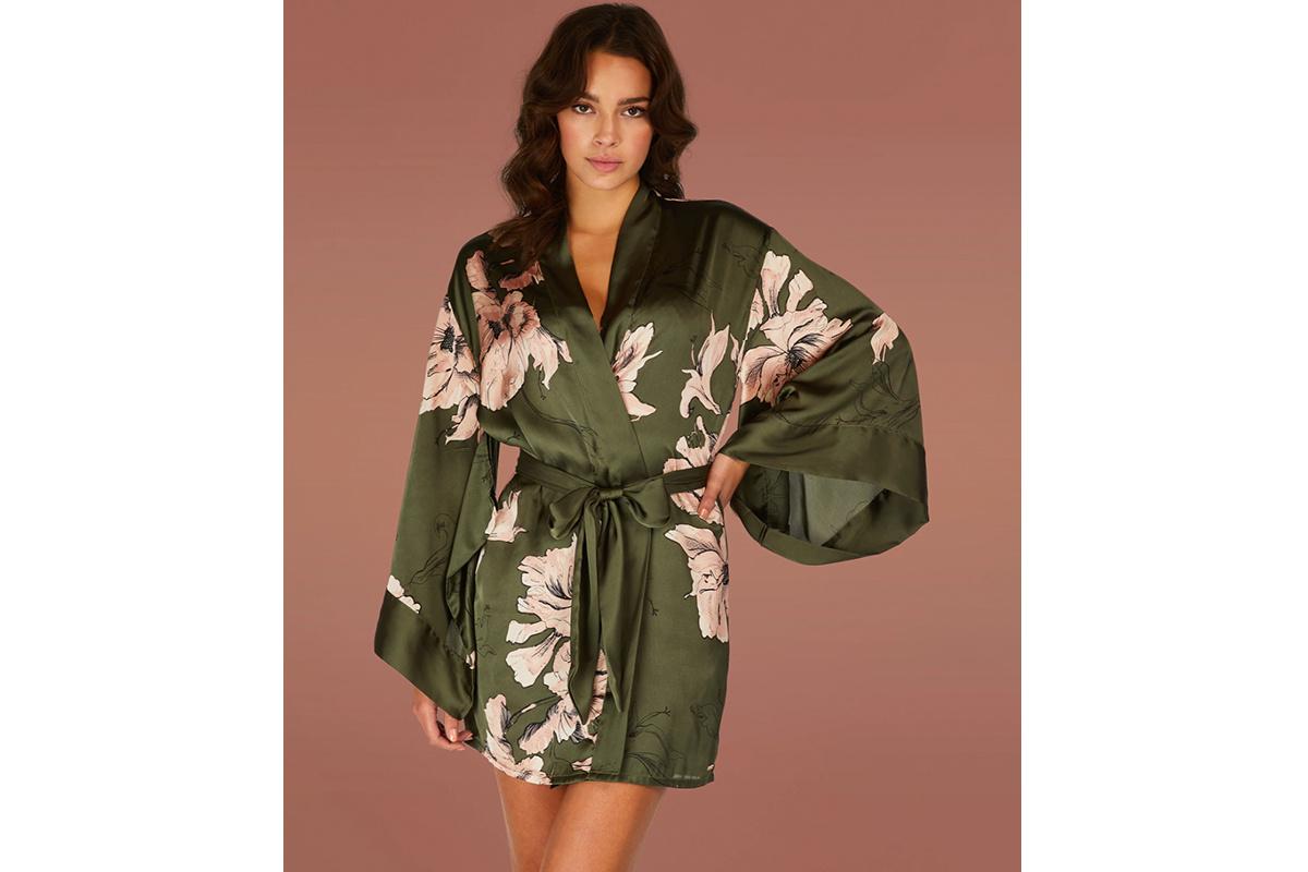 Chica con un kimono corto estampado con motivos florales en rosa sobre fondo verde