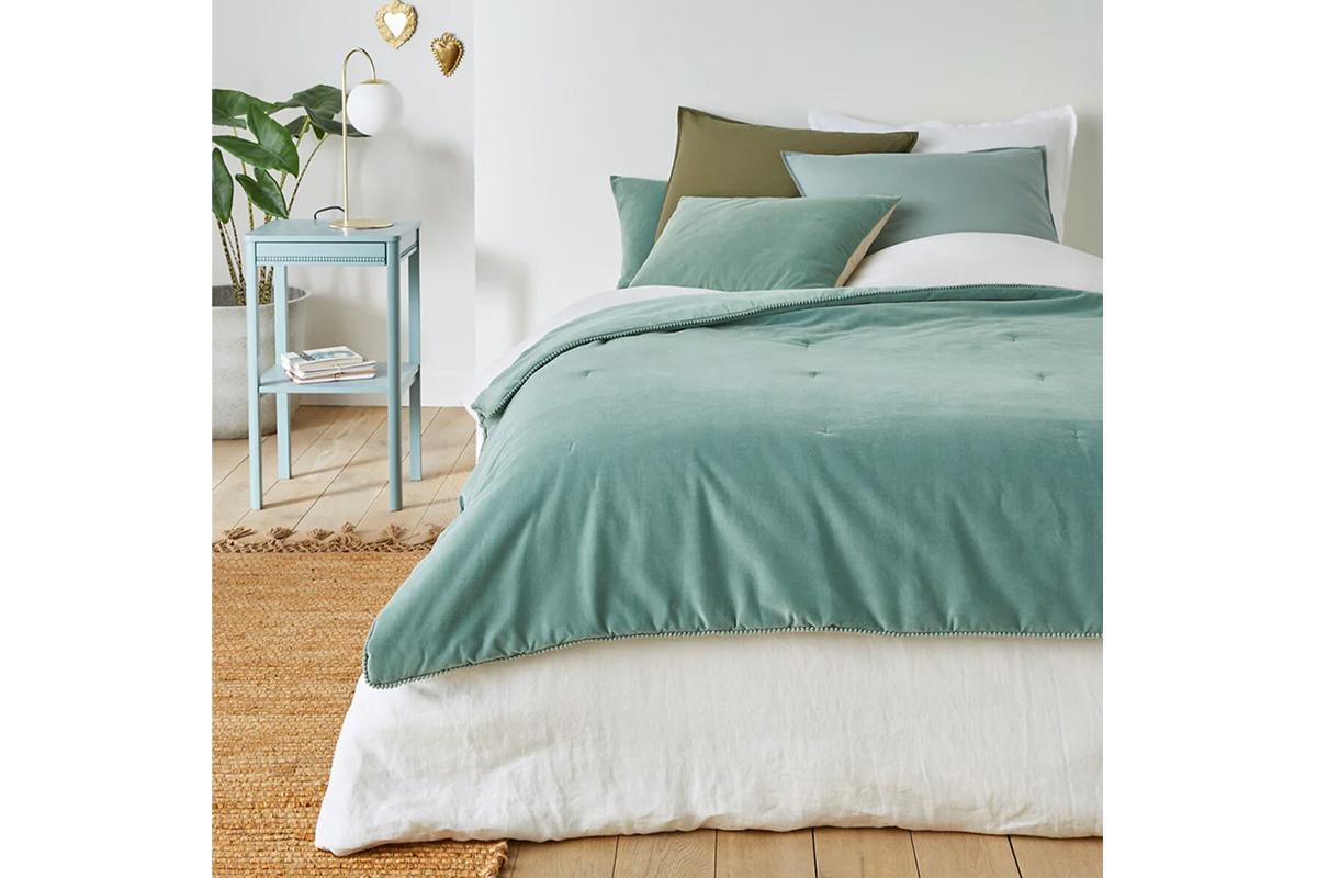 Edredón aterciopelado en color verde encima de una cama de matrimonio
