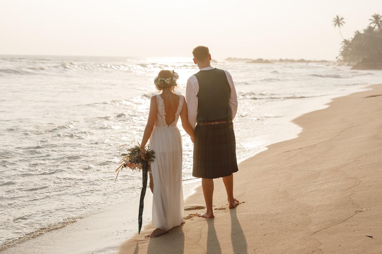 Boda celta: pareja de recién casados de espaldas a orillas del mar, él con falda escocesa