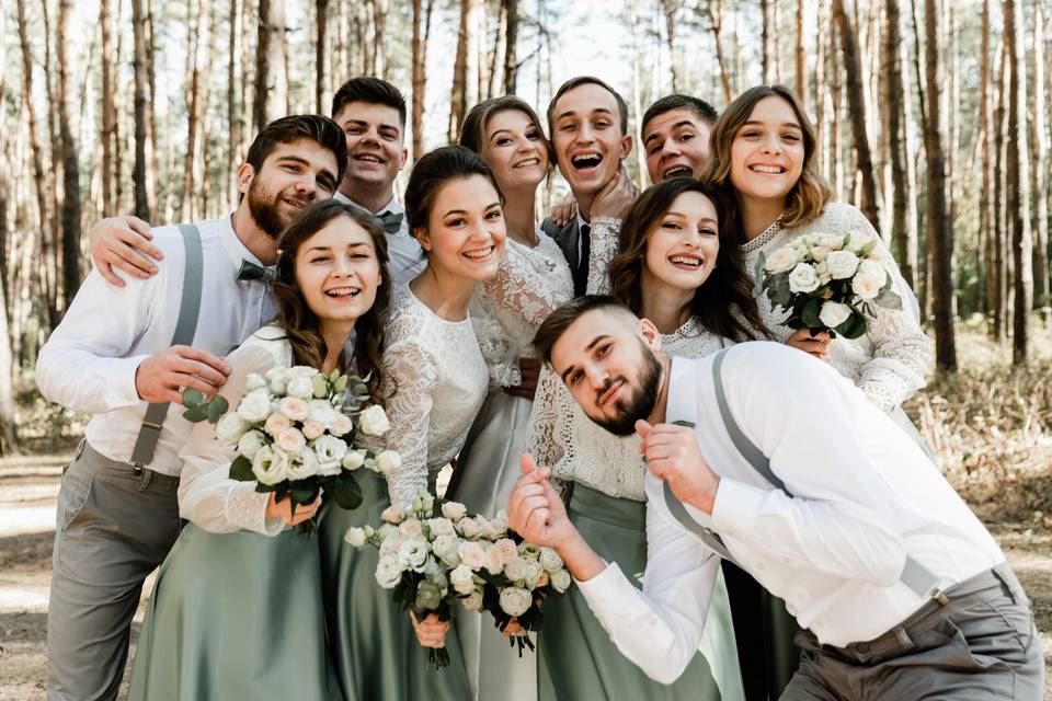 Grupo de amigos y amigas elegantemente vestidos posan junto a una pareja vestida de novios