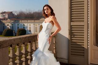 Chica en una terraza con un vestido de novia de aire flamenco con volantes en el bajo de la falda y escote corazón