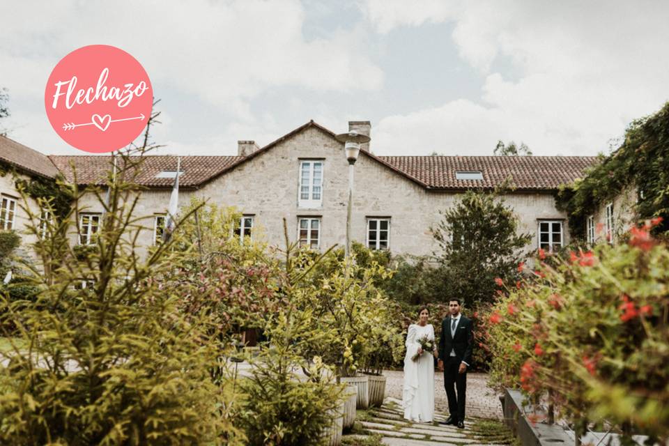 Pareja de chico y chica el día de su boda en un jardín delante de un pazo en Galicia: Hotel Spa Relais & Chateaux A Quinta da Auga