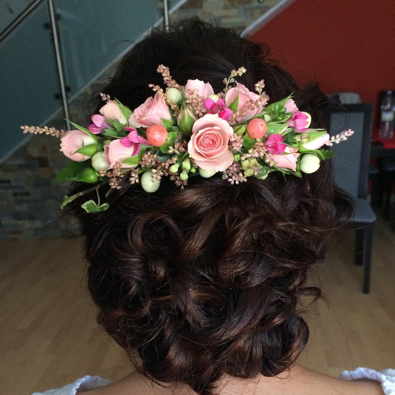 Peinados invitada boda pelo rizado: trenza en pelo moreno rizado con tocado de fllores