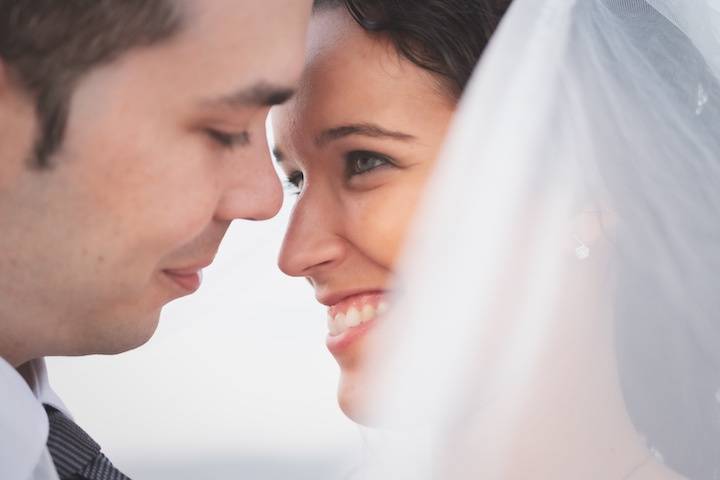 Canciones vídeo boda: chico y chica, con velo, mirándose fijamente a los ojos y a punto de besarse