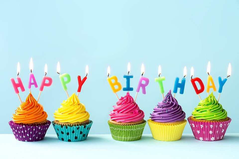 Cupcakes de colores con velitas encendidas en las que se lee Happy birthday