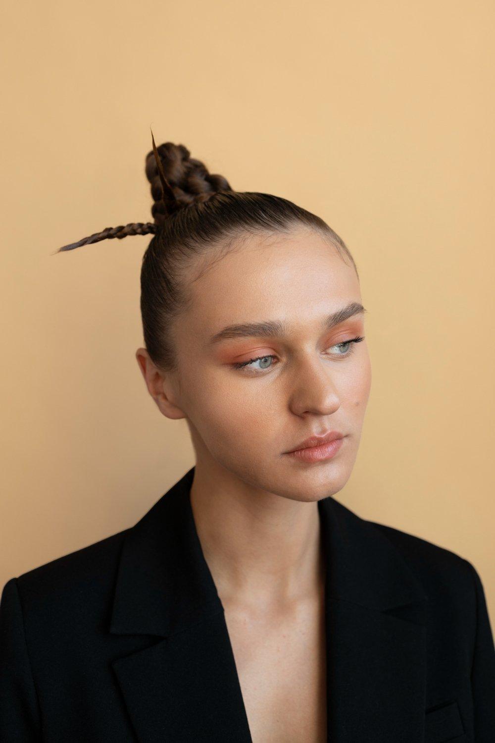 peinados trenzas boda: primer plano de mujer con ojos claros y pintada con sombra de ojos naranja con un moño tp knot con trenza enrollada.
