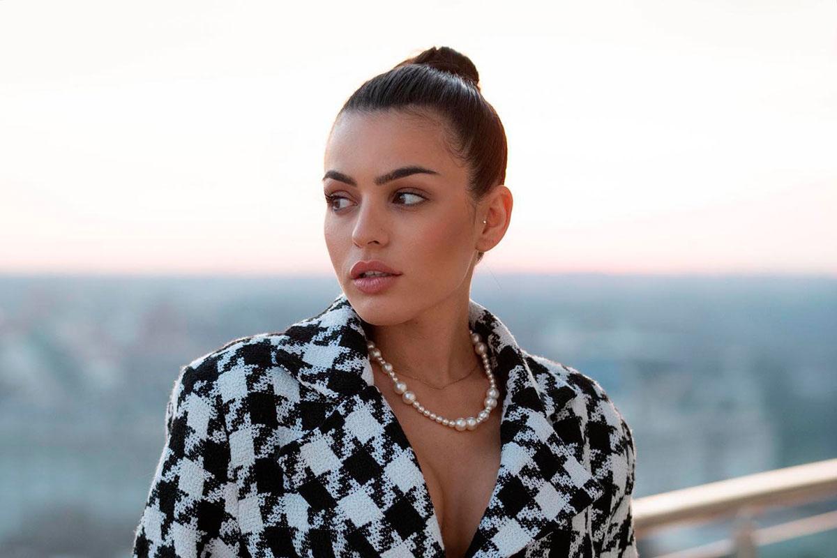 Anabel Hernández en un primer plano con moño alto top knot y una chaqueta blanca y negra con escote en V y collar