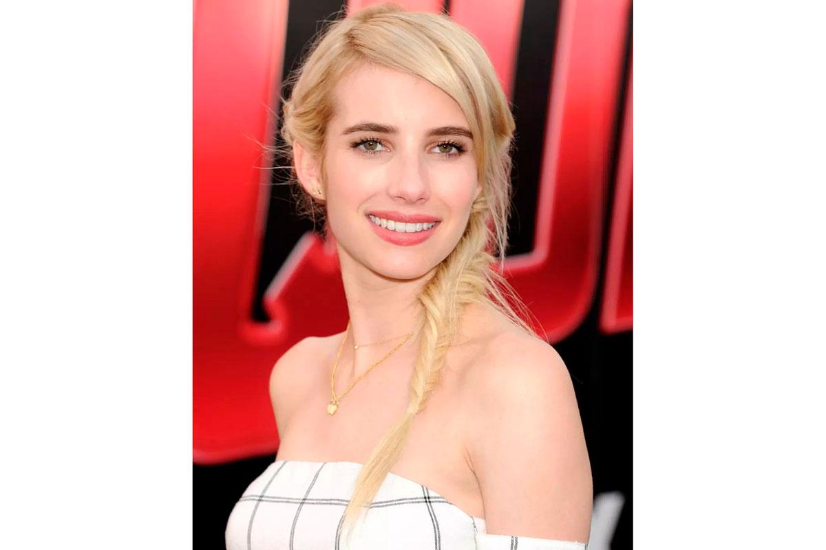 Emma Roberts mirando a cámara peinada con una trenza deshecha larga de estilo romántico y boho