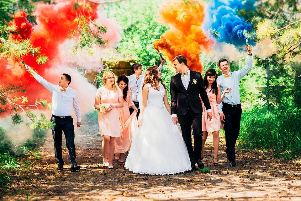 Novios e invitados de boda con humo de colores