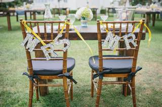 Letras sujetas con cintas en las sillas de los novios el día de la boda en las que se lee Mrs. y Mr.