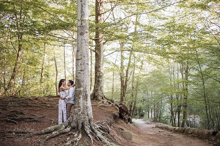 Pareja se abraza apoyados en un árbol en medio de la montaña