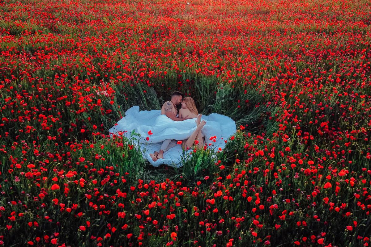 Qué regalar a tu pareja por San Valentín: pareja de chico y chica en mitad de un campo de amapolas rojas