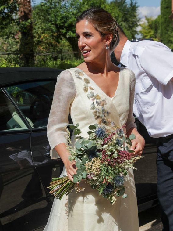 Detalle de las flores en tonos pastel del vestido de novia de María Corsini y su ramo de novia silvestre