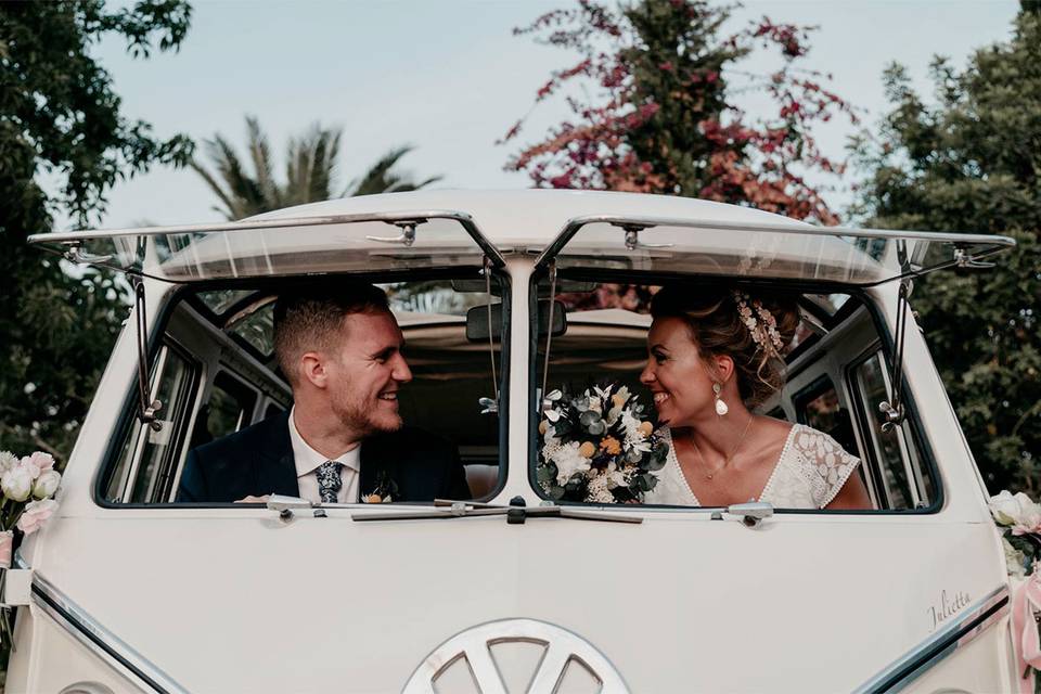 pareja de chico y chica vestidos de boda en una furgoneta volkswagen retro