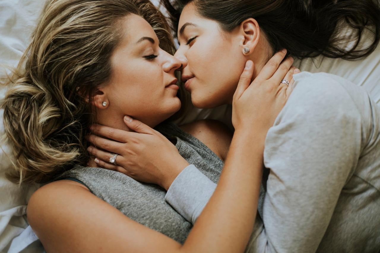 Preguntas sobre sexo: dos chicas estiradas en una cama, en actitud cariñosa, a punto de darse un beso